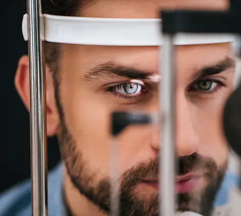 A man with blue eyes looking into the mirror.